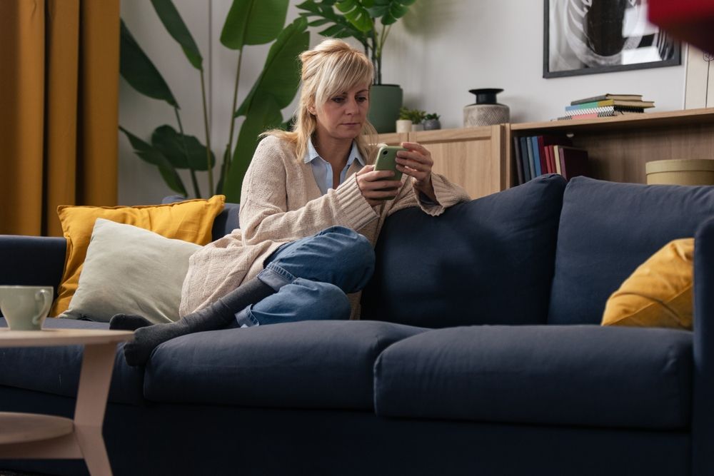 A woman sitting on a couch, holding a phone
