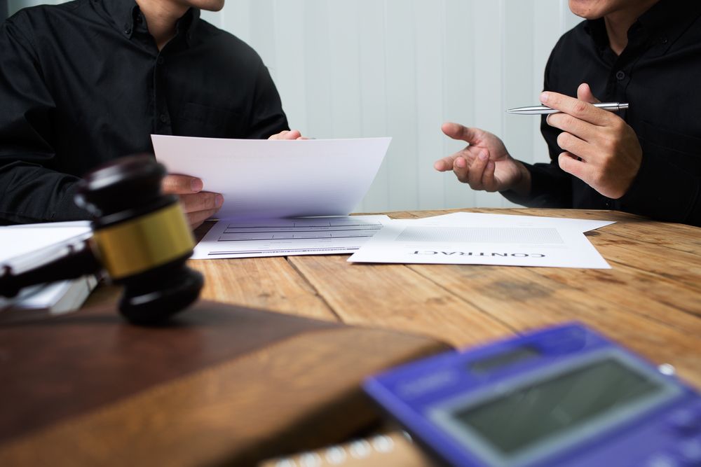 Two men seated at a table with a gavel and papers, engaged in a discussion or meeting.