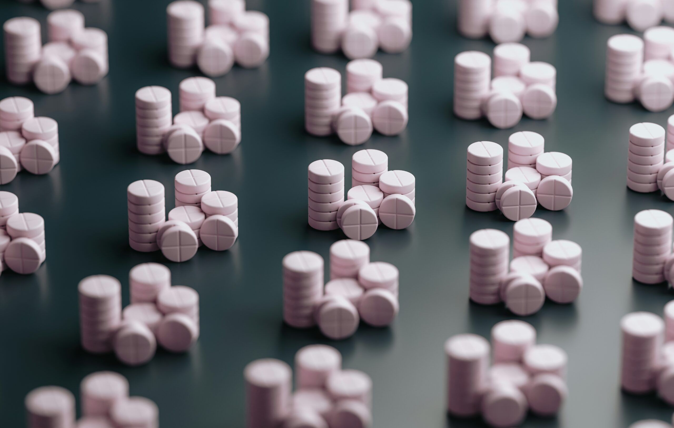 neat, identical stacks of while pills on a dark surface