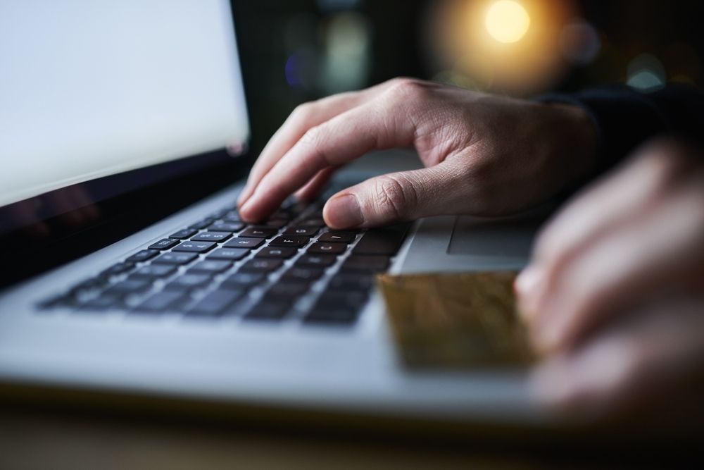 Hands, laptop and credit card fraud for hacking, cloning and identity theft with man typing at night. Hacker, tech and software for cyber crime, phishing scam or subscription with banking eft wire