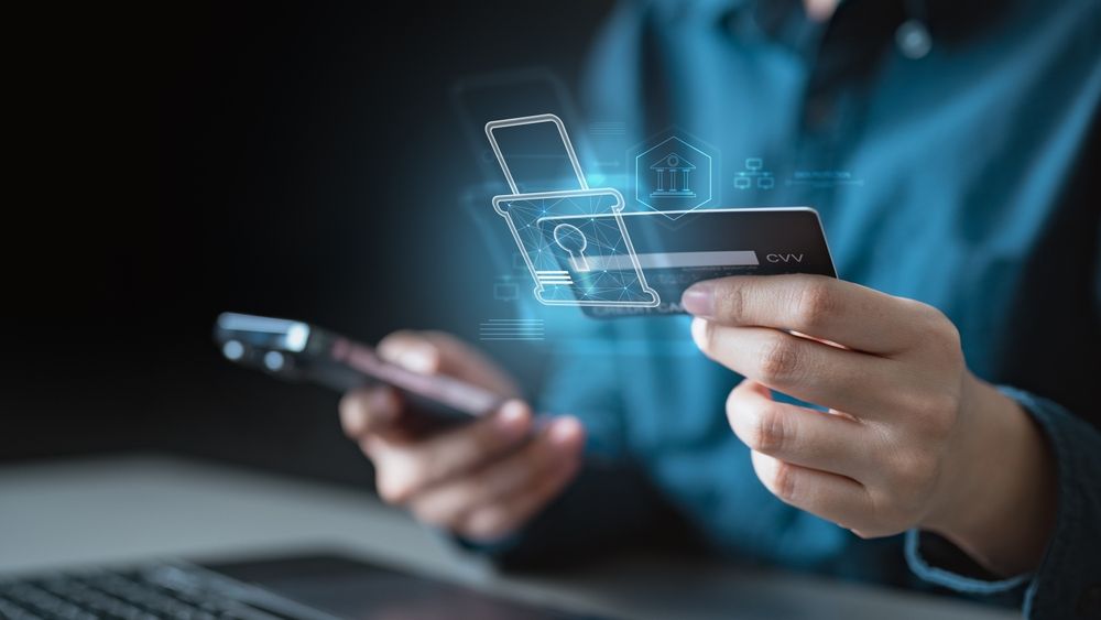 A person holding a credit card and smartphone using 2FA or OTP verification, representing secure online payment and fraud prevention
