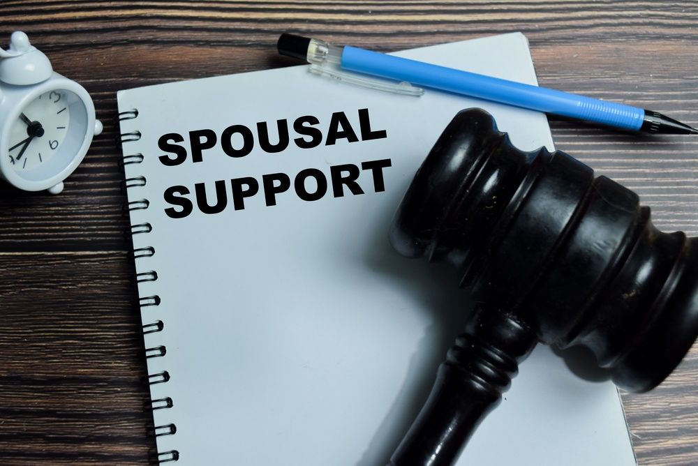 Image depicting spousal support during a divorce, with legal documents and a calculator on the table.