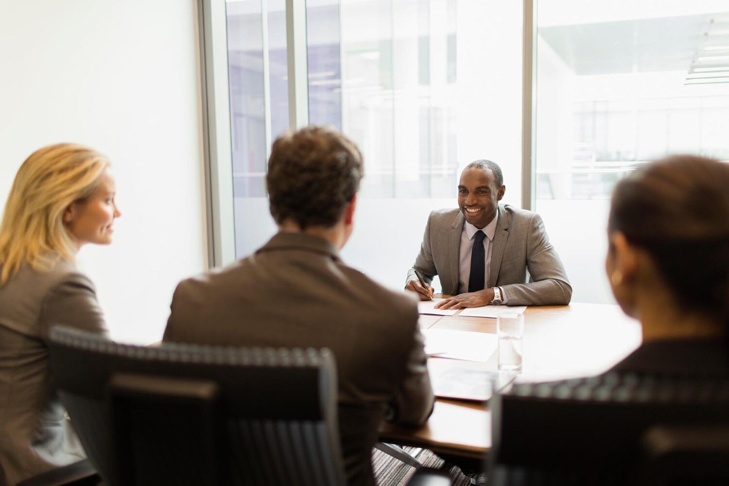 
                    Friendly, Black, male lawyer meeting with clients at his desk.