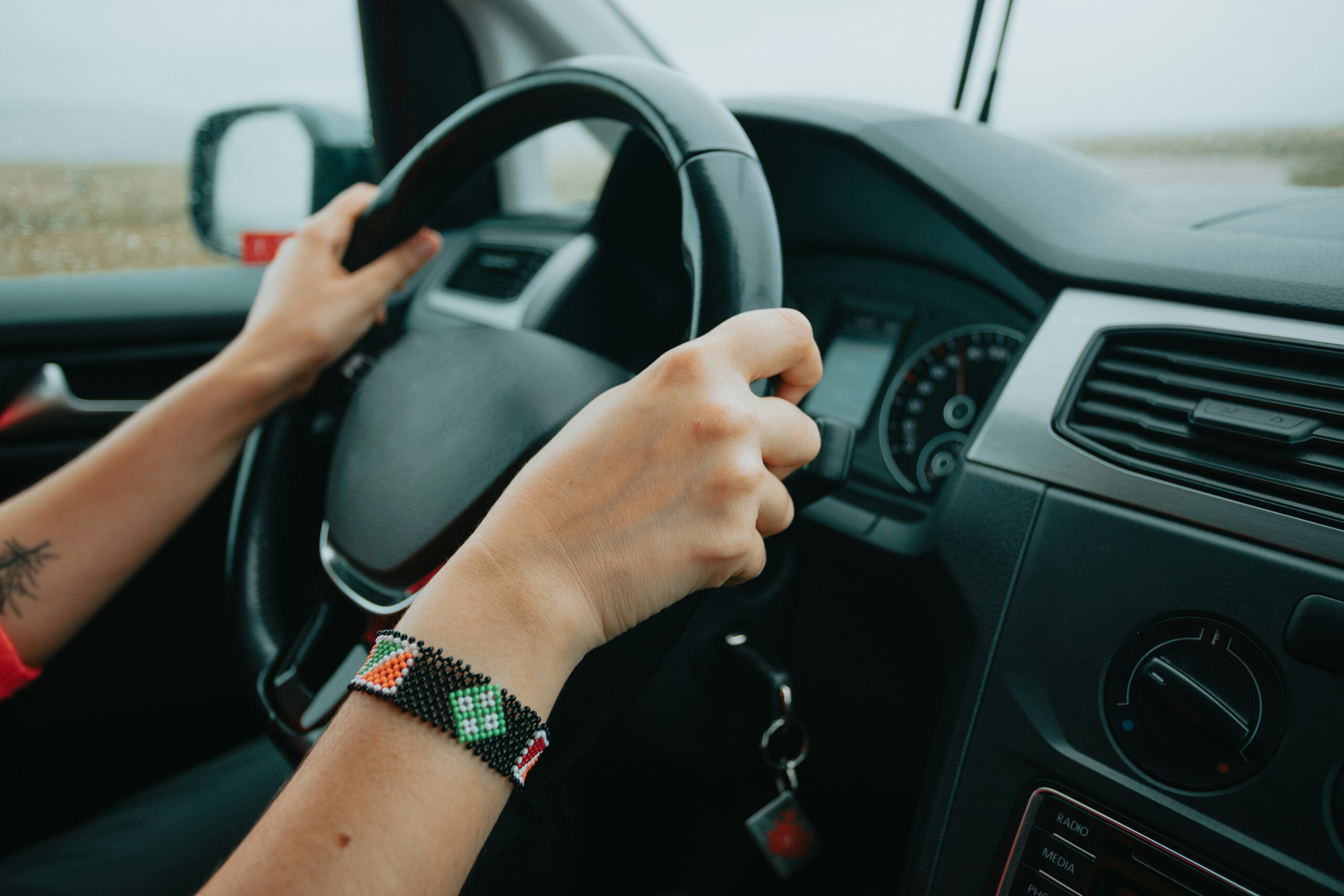 A woman driving a car, focused on the road with her hands firmly on the steering wheel.