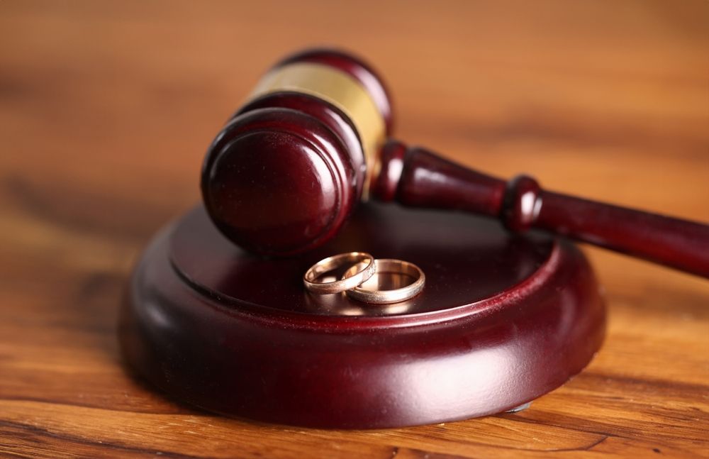 Two wedding rings resting on the sound block of a gavel